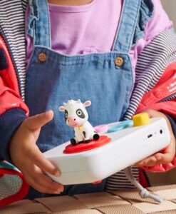 Niña sujetando el cuentacuentos FABA+ blanco con la figura de la vaca de las canciones del mundo