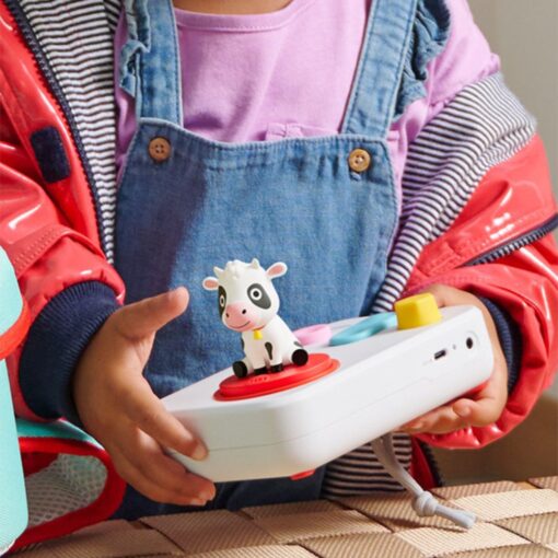 Niña sujetando el cuentacuentos FABA+ blanco con la figura de la vaca de las canciones del mundo