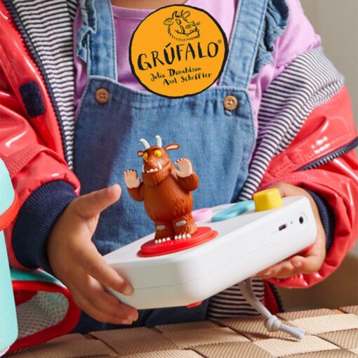 A little girl holding the white FABA+ storybook with the Gruffalo figure placed on the red disc
