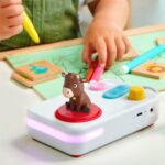 Mà d'un infant amb un retolador al costat del contacontes FABA+ amb el bou d'El Patufet en català