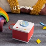 Red FABA children's storyteller with *The Little Prince* CD, sitting on a rug next to a wooden rainbow