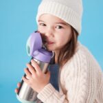 Niña bebiendo por la pajita de silicona de la botella térmica b.box morada