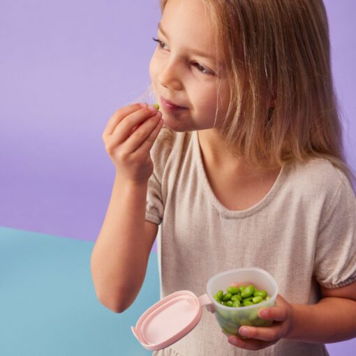 Niña comiendo de un depósito hermético b.box abierto, con la tapa colgando de la bisagra