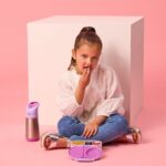 Niña sentada en el suelo comiendo de la fiambrera de snacks b.box abierta