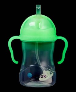 Vaso con pajita b.box brillando en verde en la oscuridad, con las asas y la pajita visibles