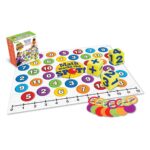 Caja de Math Marks the Spot de Learning Resources junto a la alfombra desplegada, los dados y las fichas
