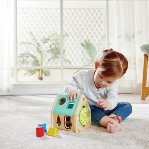 Clasificador Casa de Criaturas de Hape: niña jugando sola en el suelo con la casita y los bloques de colores