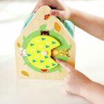 Clasificador Casa de Criaturas de Hape: manos girando la rueda lateral de colores que descubre a los animales
