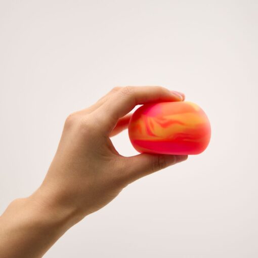 Gradient Squishy de J'adore: mano sujetando un squishy rojo y naranja con vetas de color