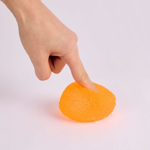 Gum Droppable de J'adore: dedo aplastando una gominola naranja que se deforma al apretarla