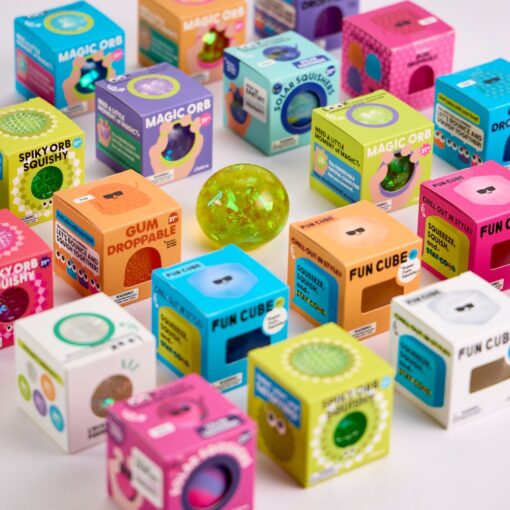 Magic Orb de J'adore: un squishy verde con brillos entre cajas de colores de otros squishies