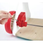 Andador musical de madera de Hape: adulto ajustando con una llave el mecanismo del eje junto a la rueda trasera