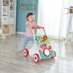 Andador musical de madera de Hape: bebé caminando por el salón agarrado al asa roja del andador