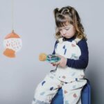 Botella sensorial Ballena de Petit Boum: niña sentada mirando con atención la botella entre las manos