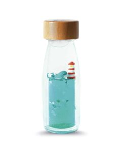 Botella sensorial Ballena de Petit Boum: botella con tapón de madera, ballena y faro rojo y blanco sobre líquido turquesa