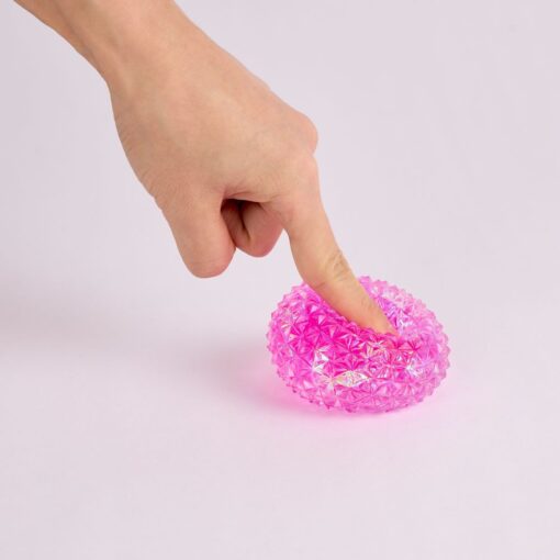 Spiky Orb de J'adore: dedo aplastando un squishy rosa con pinchos y brillos por dentro