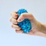 Spiky Orb de J'adore: mano apretando con fuerza un squishy azul que se deforma entre los dedos