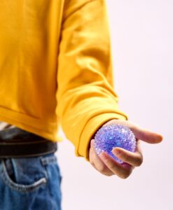 Spiky Orb de J'adore: niño con jersey amarillo sujetando un squishy lila con la mano abierta