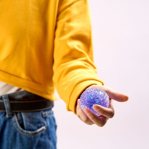 Spiky Orb de J'adore: niño con jersey amarillo sujetando un squishy lila con la mano abierta