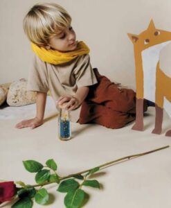 Botella sensorial El Principito de Petit Boum: niño con bufanda amarilla mirando la botella en el suelo
