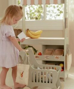 Carrito de la compra de Little Dutch: niña empujando el carrito junto a un puesto de mercado de juguete