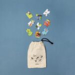 Puzzle reversible de montaña de Londji: bolsa de tela con cordón de la que salen las piezas