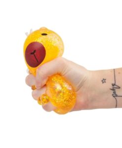 Capibara squishy Sugar Capybara: mano apretando la capibara amarilla, que se deforma con la purpurina dentro